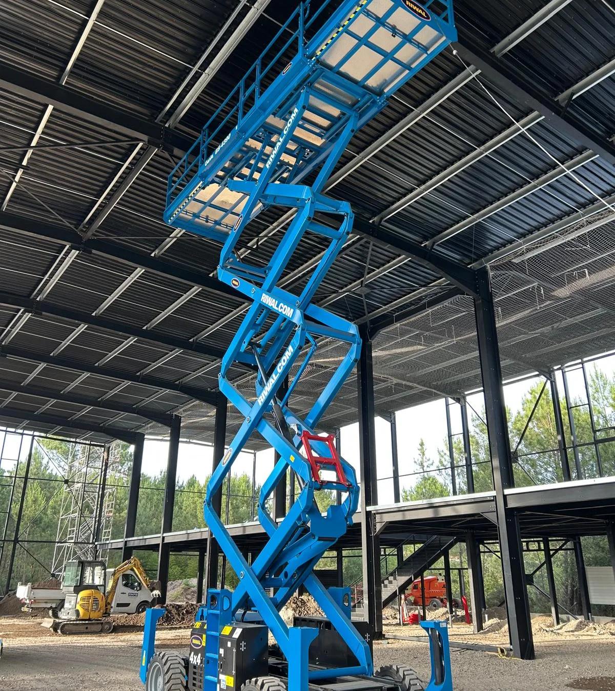 Nacelle ciseaux bleue dans un bâtiment industriel en construction